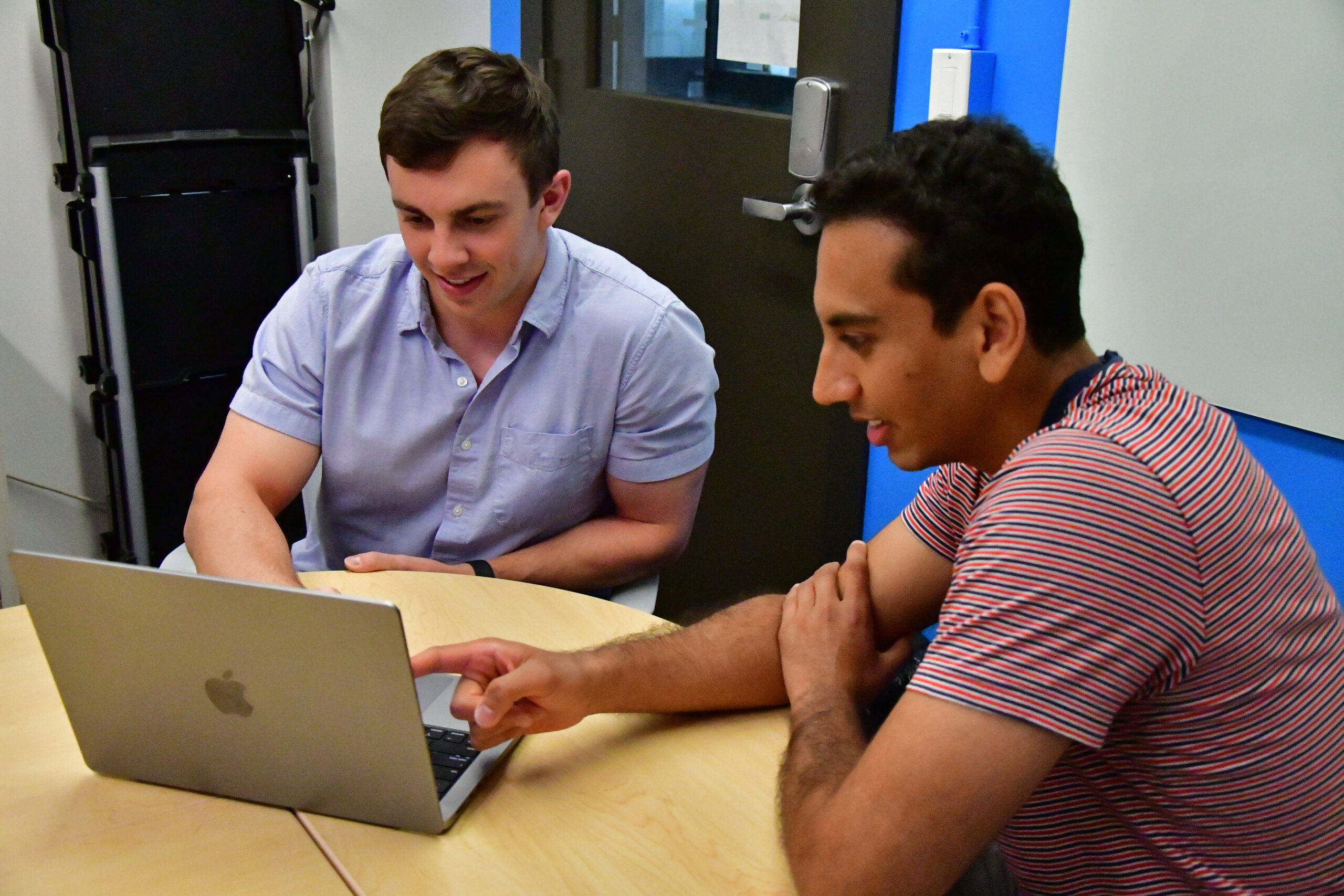 Two students looking at a laptop, with one pointing at the screen.