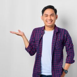 Male student presents an invisible object against a grey background.